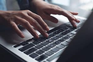 Close-up of businesswoman's hands typing on laptop.