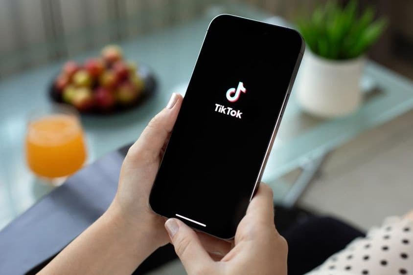 Woman holding Apple iPhone with TikTok on screen.
