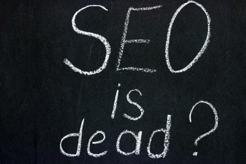 Is SEO dead? inscription on a chalk board against a dark background.